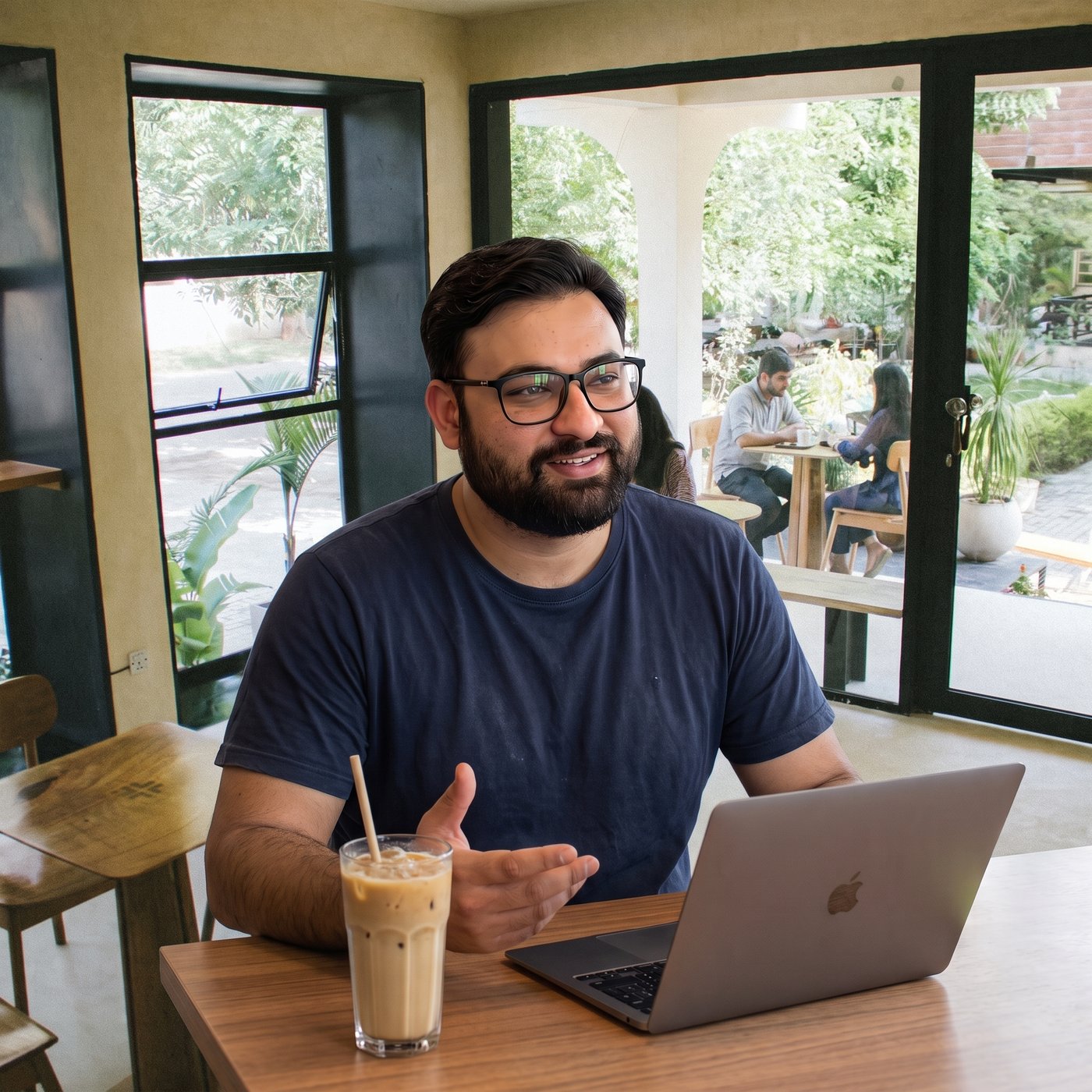 Ali Ahmed Awan working at a laptop in a sunlit café